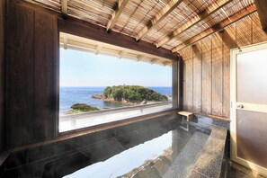 A room with a large window overlooking a coastal landscape, a polished black floor, and wooden paneling on the walls. - Ocean View Hiromi SPA Hotel (Shimoda)