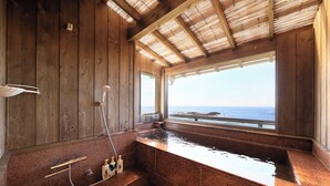A wooden interior with a hot tub, a window overlooking the sea, and a shower area. - Ocean View Hiromi SPA Hotel (Shimoda)