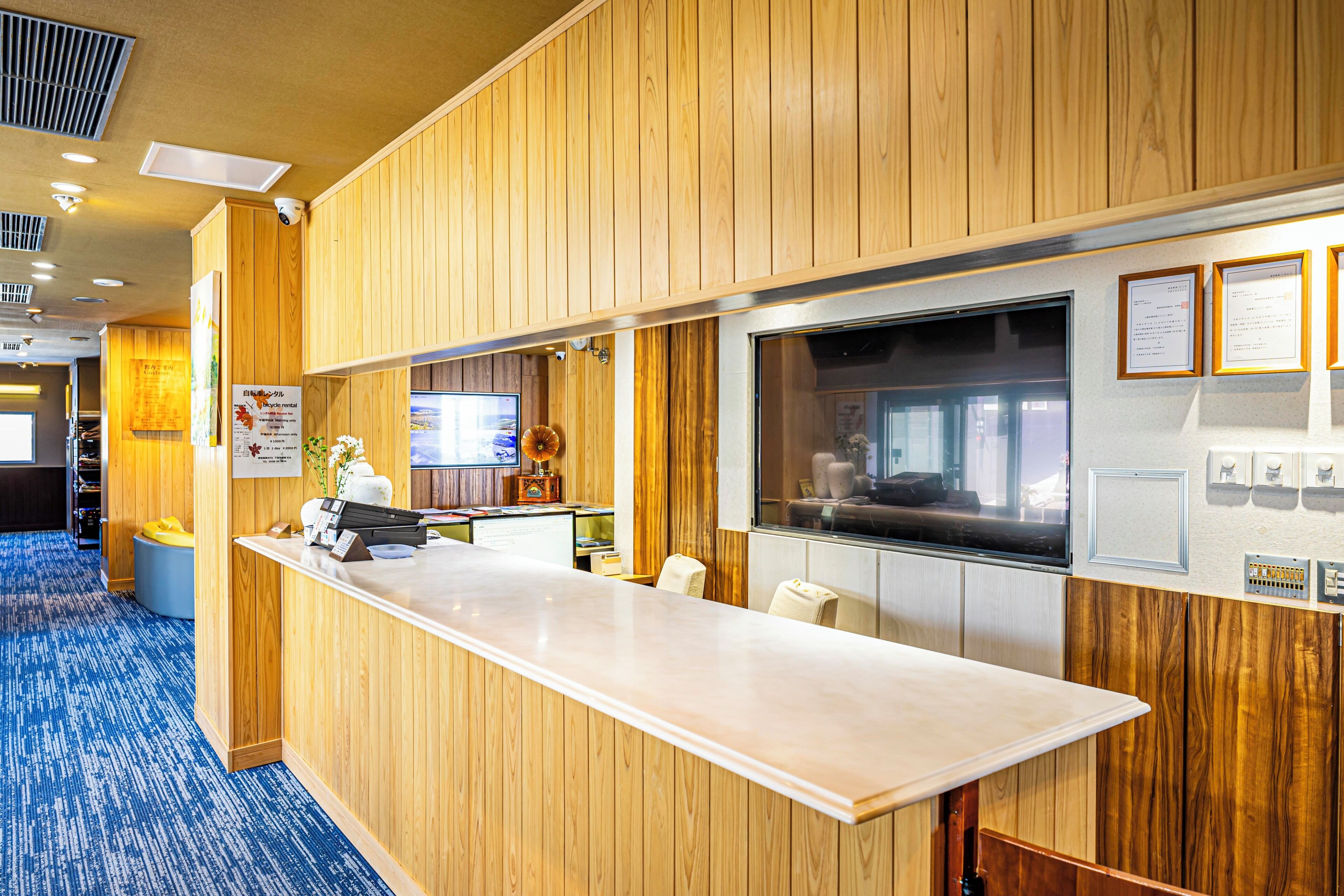 A reception area with a wooden panel wall, a reception desk, and a large window.
