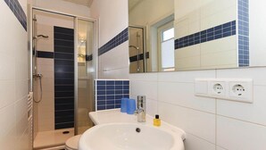 Un baño con ducha, inodoro, lavabo y espejo.