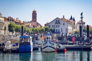 Un puerto deportivo con barcos amarrados, una torre del reloj y edificios con balcones.