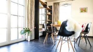 A modern dining area with a large window, a potted plant, and a dining table with chairs.