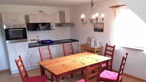 Une cuisine compacte comprenant une table et des chaises, un four encastré et un lustre.