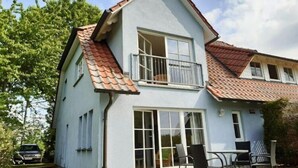 Une maison à deux étages, avec un toit en tuiles, de grandes fenêtres et un balcon.