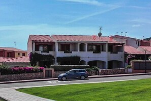 A two-story building with a red-tiled roof, a car parked in front, and a well-maintained lawn.