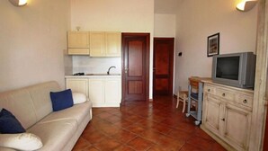 A compact living space with a kitchenette, a sofa, a television, and a cabinet. - Apartment in Cannigione (Cannigione)
