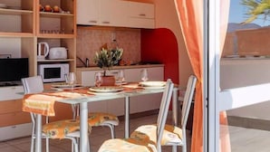 A modern kitchen with white cabinets, a dining table set for four, and a view of the outdoors. - Residence Casa & Vela with private beach, Oggebbio (Oggebbio)