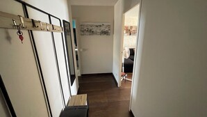 Un couloir avec un porte-manteau, une petite table et une affiche accrochée au mur.