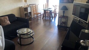 Un salon comprenant un canapé, une table basse, un téléviseur et un coin repas avec des chaises et une table.