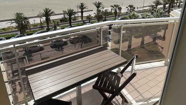 Un balcon avec vue sur la plage, une table et des chaises.