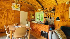 Interior de una cabaña de madera con comedor, cocina y un rincón acogedor para sentarse.