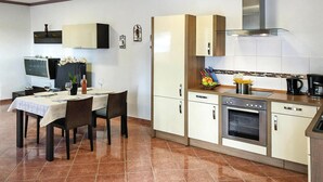 Een moderne keuken met een eethoek, met een ingebouwde oven, een koffieapparaat en een schoolbord.