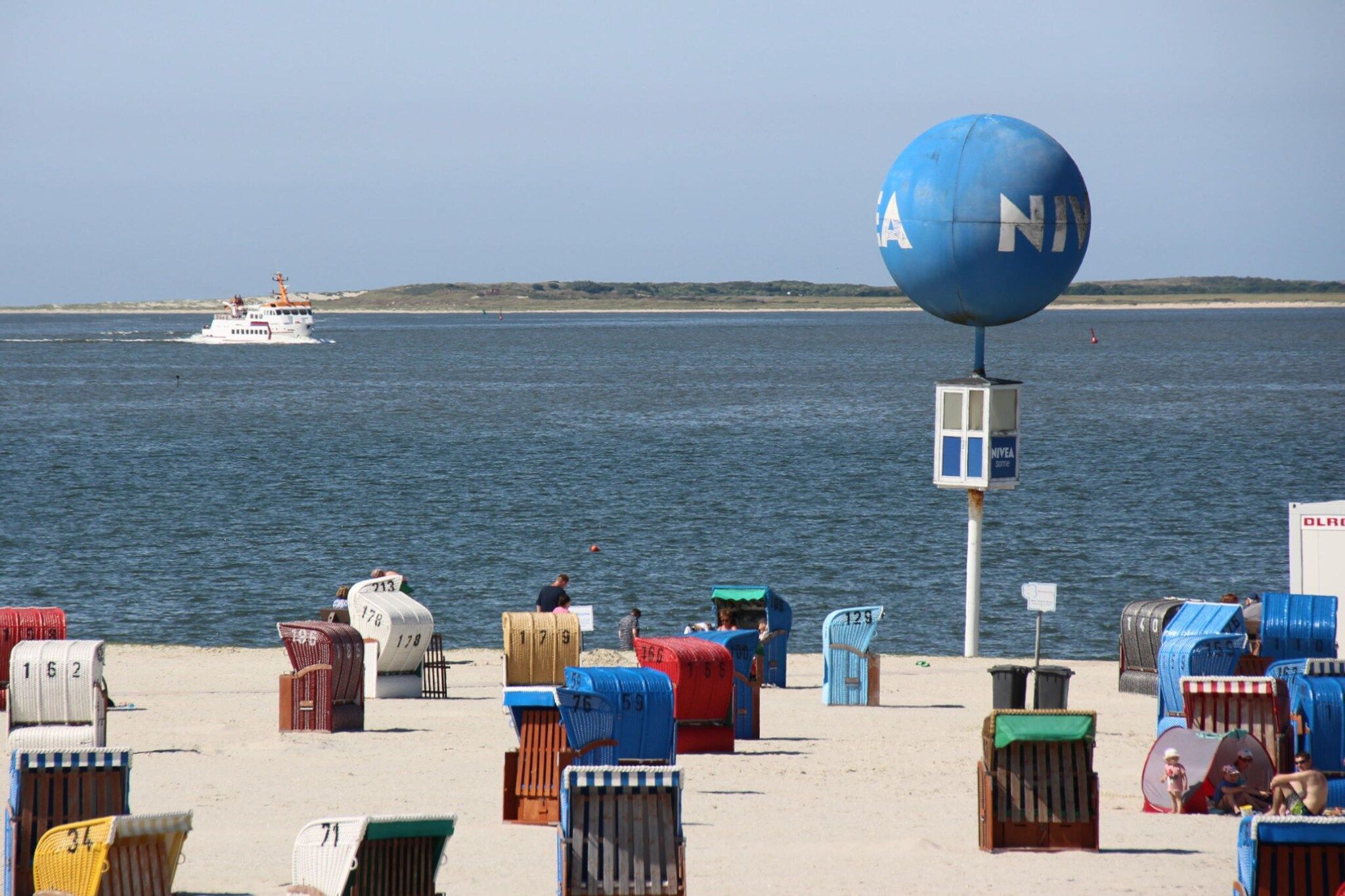 A beach with numbered beach chairs and a large blue sign.