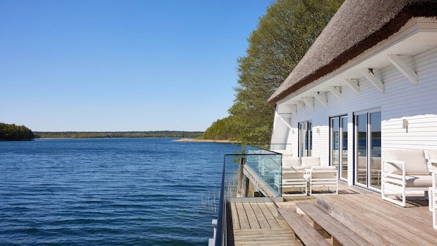 A waterfront property with a wooden deck, white exterior, and large windows.