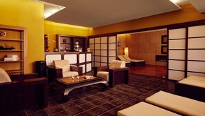Een moderne woonkamer met donker houten vloeren, een zithoek, een salontafel en een klein eethoekje met een tafel en stoelen.
