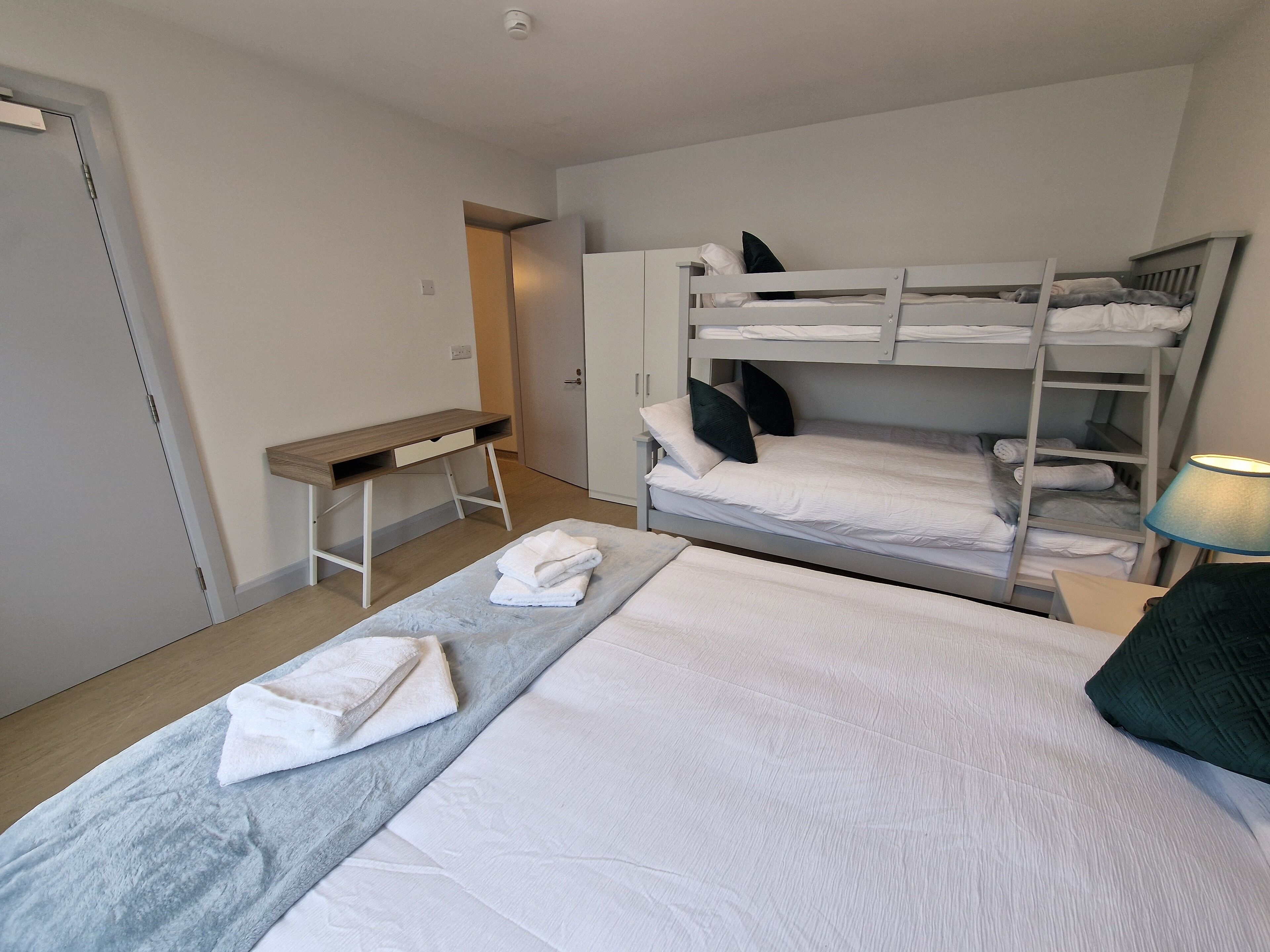 Et værelse med køjeseng, skrivebord og lampe.