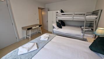 Et værelse med køjeseng, skrivebord og lampe.