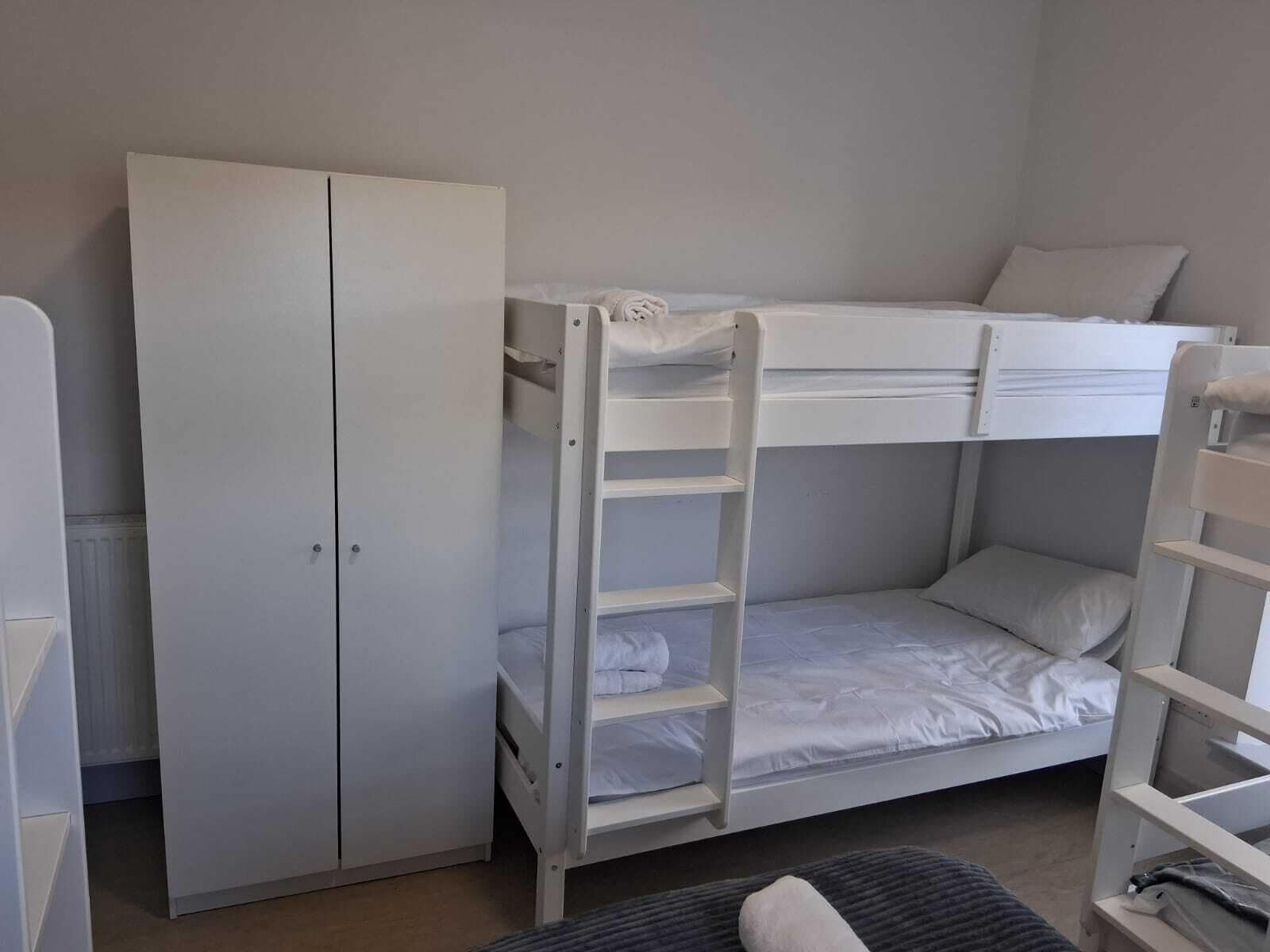 Ein Stockbett mit einer Leiter, ein Kleiderschrank und ein Nachttisch in einem Zimmer.