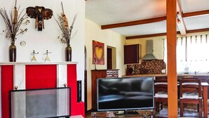 A living room with a fireplace, a TV, and a dining area with wooden chairs. - Ferienwohnung am Kummerower See, Sommersdorf (Sommersdorf)