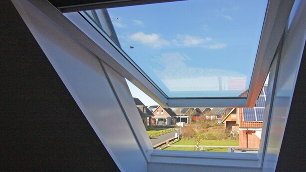 A skylight window with a view of residential houses and solar panels. - Ferienwohnung im Reihenhaus, Friedrichkoog-Spitze (Friedrichskoog-Spitze)