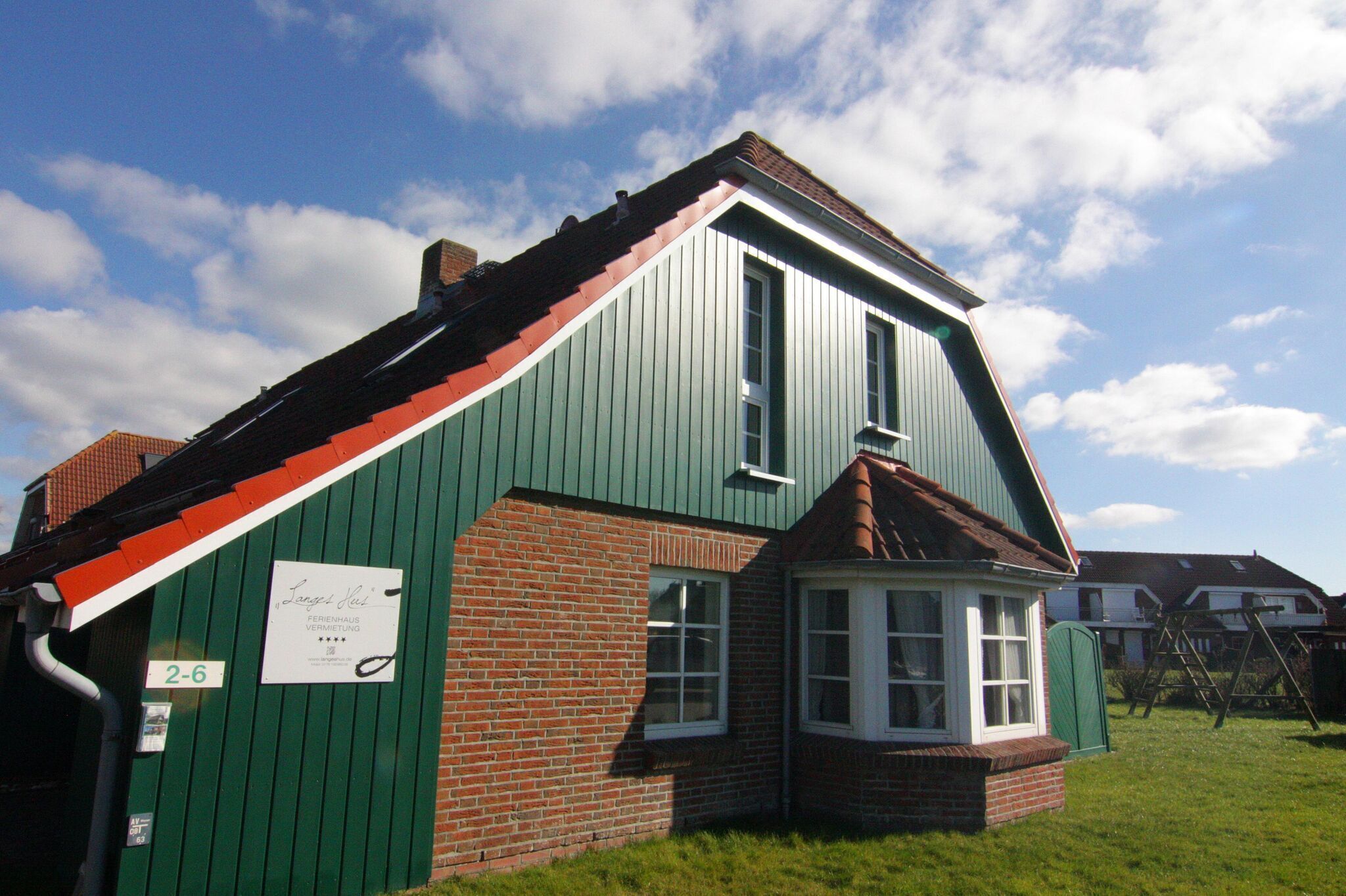 A green and red building with a small window and a sign on the side.