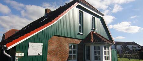 A green and red building with a small window and a sign on the side.