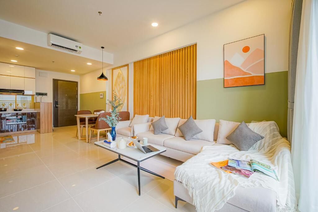 A modern living room with a sofa, coffee table, and dining area. There is a kitchen in the background.