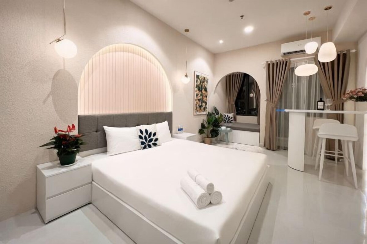 Une chambre d’hôtel moderne, dotée d’un grand lit, de tables de chevet, d’un bureau et d’une chaise.