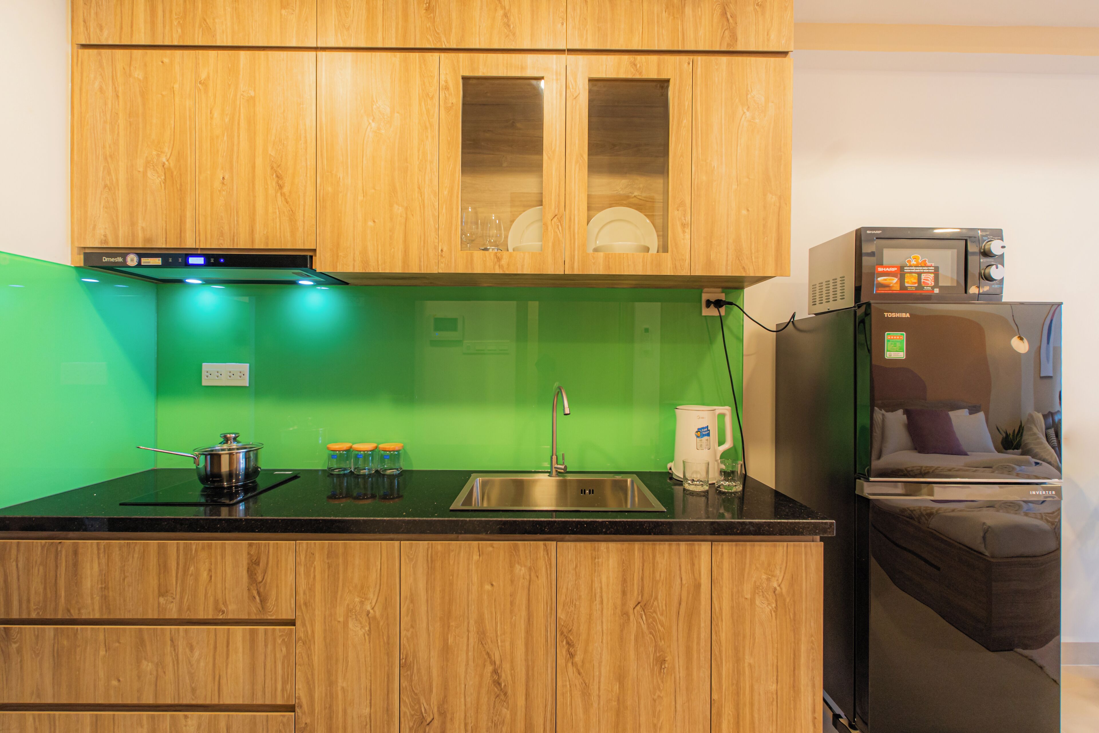 A kitchen with wooden cabinets, a black countertop, a sink, a stove, and a microwave.