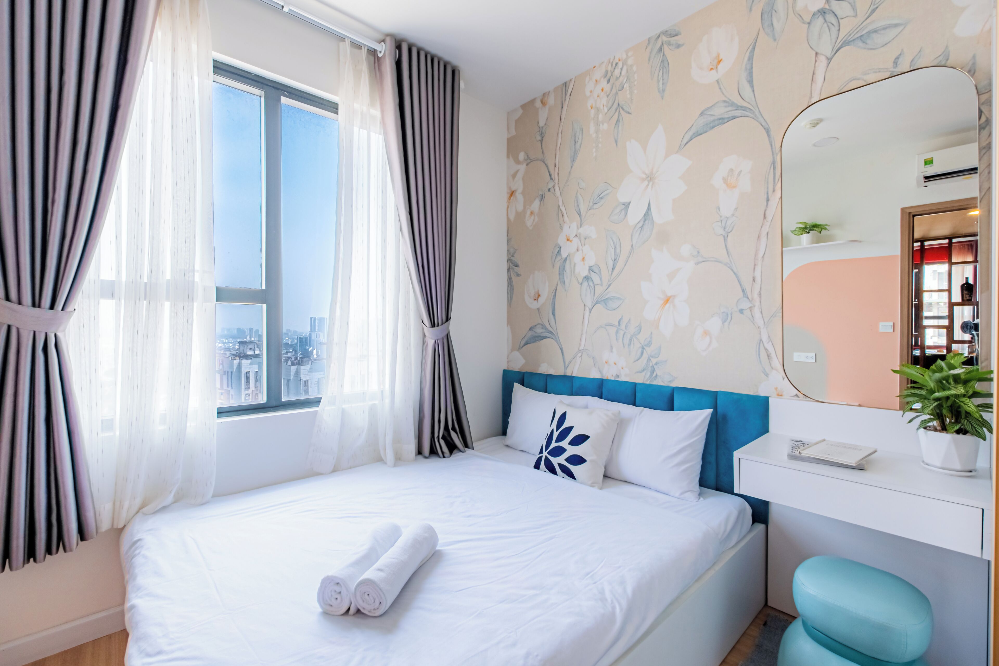 Een hotelkamer met een groot bed, een nachtkastje, een spiegel en een raam met gordijnen.