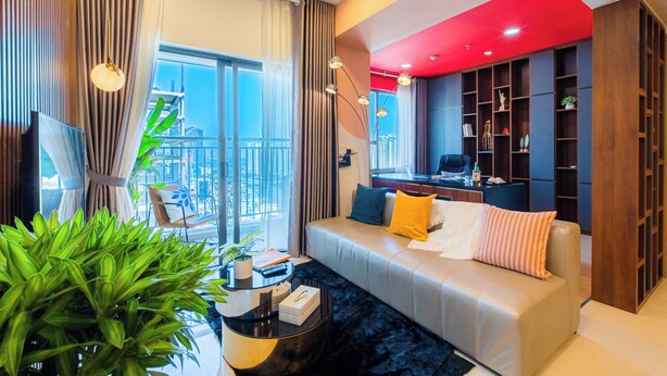 Un salon moderne avec un canapé, une table basse et un téléviseur. Il y a un balcon avec vue sur la ville.