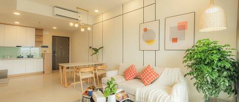 A modern living room with a sofa, coffee table, and a dining area.