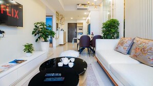 Un salon moderne avec une table basse noire, un canapé blanc et un téléviseur diffusant du contenu de « FLIX ».