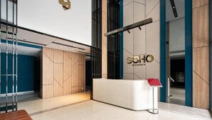 Un espace d’accueil moderne avec un mur lambrissé en bois, un comptoir d’accueil blanc et un mur d’accent bleu.