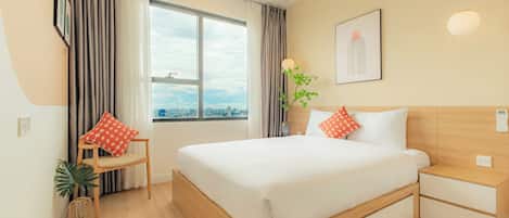 A modern hotel room with a large bed, a wooden nightstand, a bedside table, a window with curtains, a potted plant, and a city view.