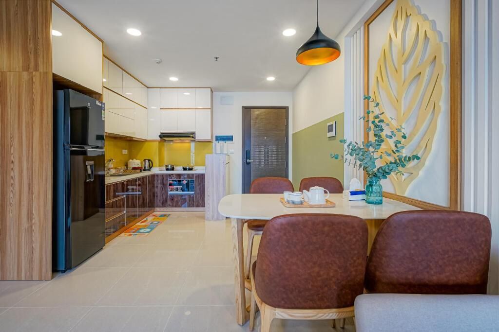 A modern kitchen with white cabinets, a black refrigerator, and a dining area with a table and chairs.