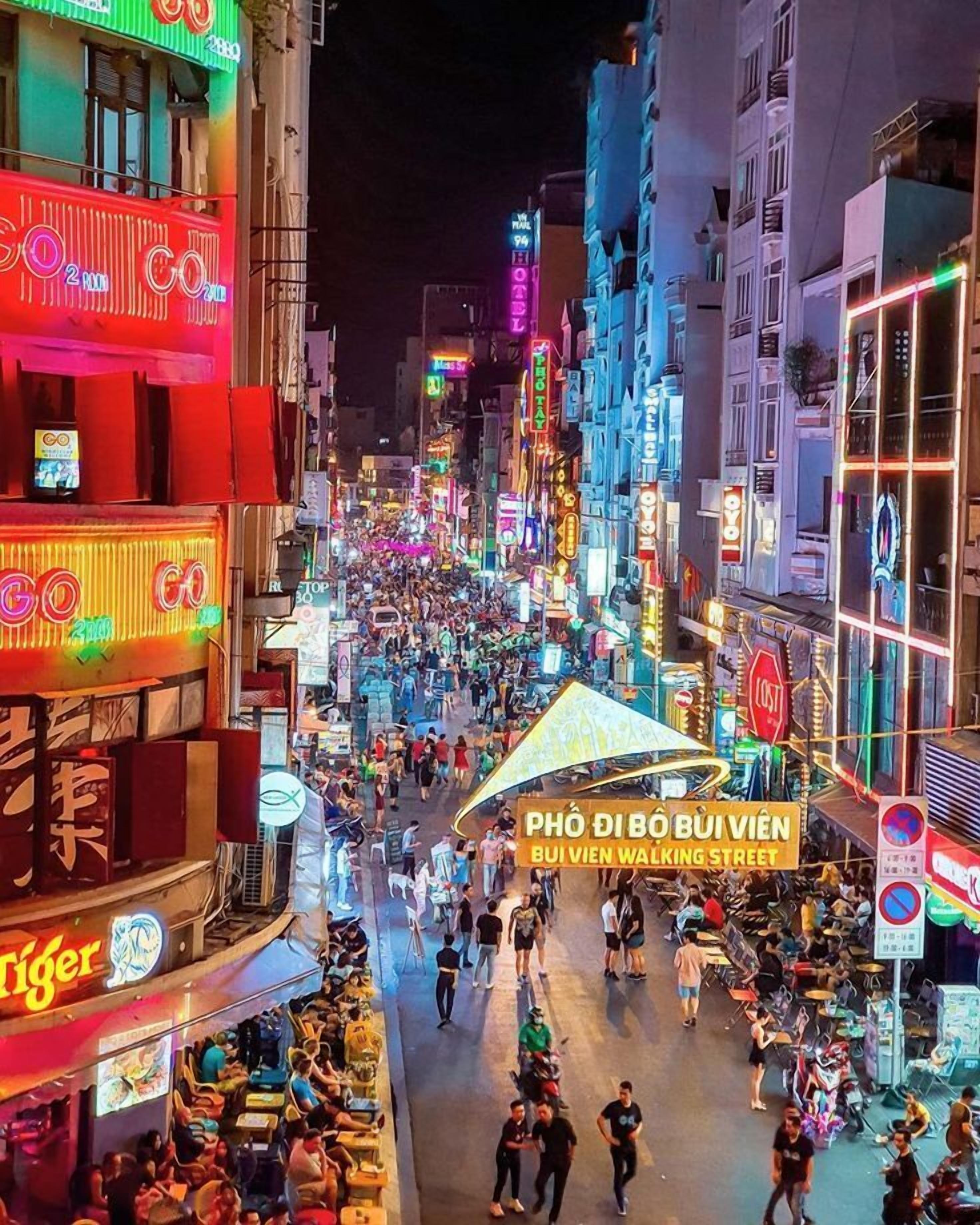 A bustling street with neon signs and a crowd of people.