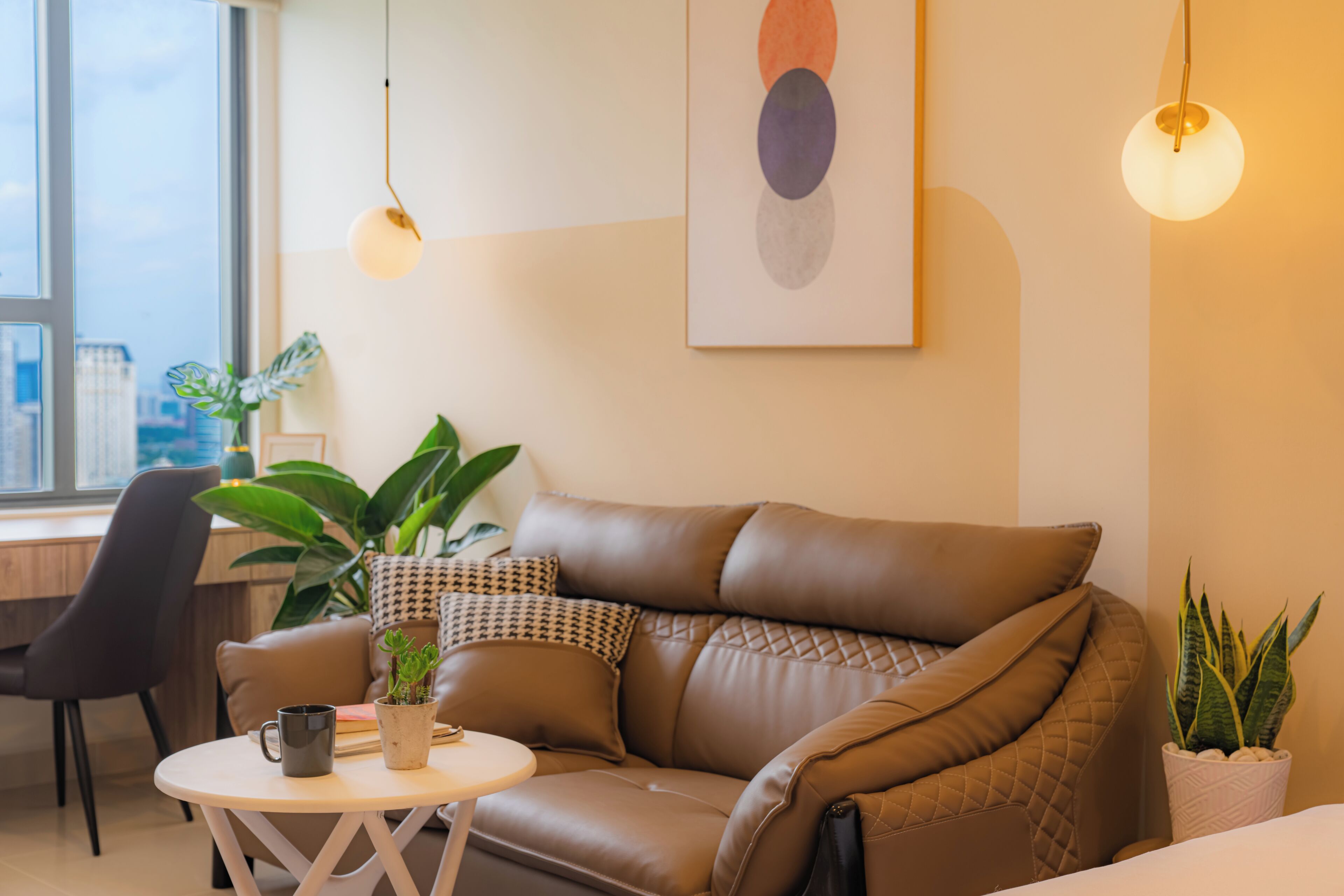 A modern living room with a brown leather sofa, a round white coffee table, and a potted plant.