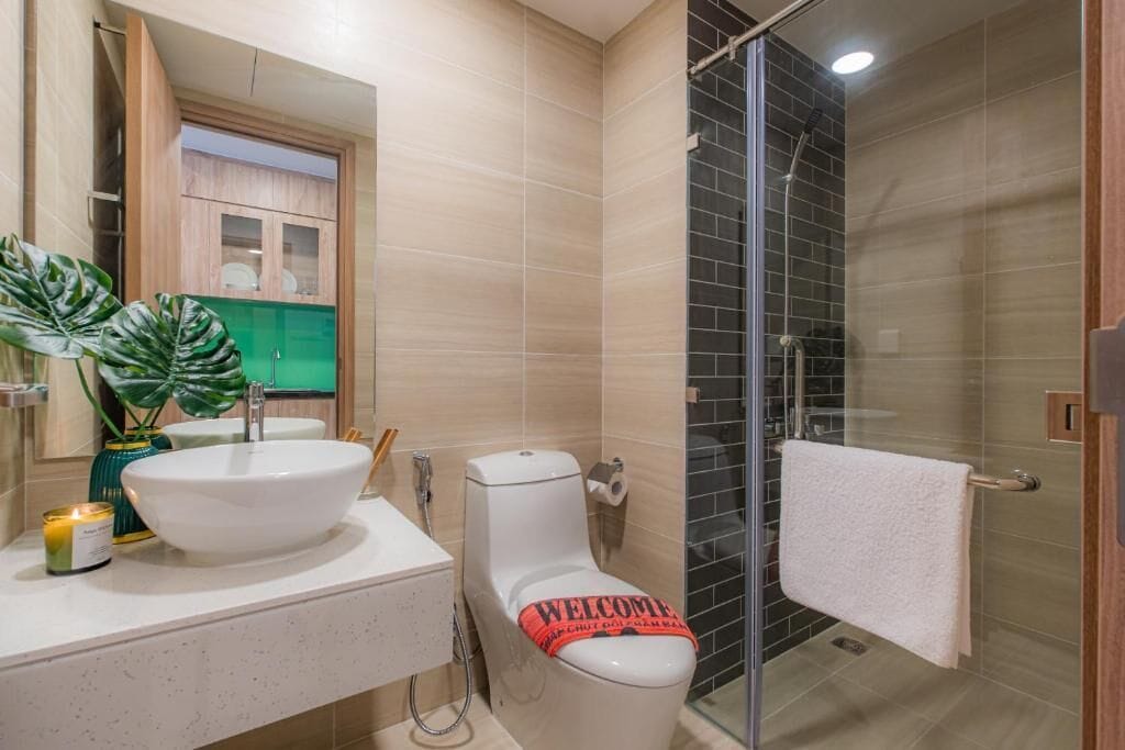 A modern bathroom with a large sink, toilet, and glass shower enclosure.