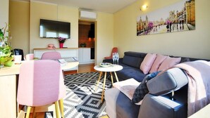 A modern living room with a sofa, a dining table, and a TV.