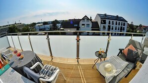 A rooftop terrace with a pool, lounge chairs, and a table with drinks.