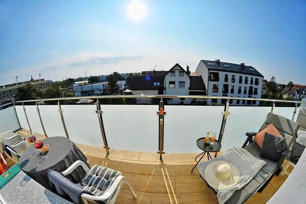 A rooftop terrace with a pool, lounge chairs, and a table with drinks.