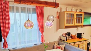 A cozy living room with a sofa, a small table, and a kitchen area with cabinets and appliances. - Wellness- Hottub & Sauna- Pet Friendly- Hiking (Keutschach am See)