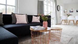 Ein modernes Wohnzimmer mit einer schwarzen Couch, einem Couchtisch und einer Topfpflanze.