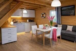 Tunnelmallinen mökin sisustus, jossa on ruokailutila, keittiö ja sohva.