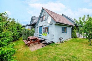 Kaksikerroksinen talo, jossa on patio, grilli ja pieni varasto.