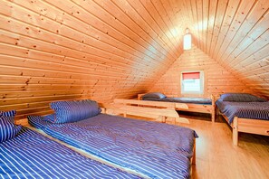 Een houten chalet met twee bedden, een raam met zonwering en een schuin dak.