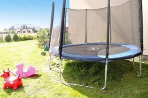 Turvaverkolla varustettu trampoliini, joka on sijoitettu nurmikolle ja jonka taustalla näkyy talo.
