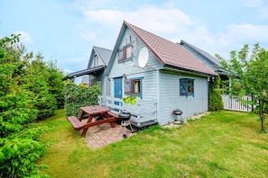 Een tweelaags huis met een veranda, een barbecue en een schotelantenne.