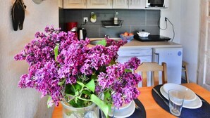 Eine Küche mit Holzausstattung, einer Mikrowelle und einem Spülbecken. Auf dem Tisch steht eine Vase mit violetten Blumen.